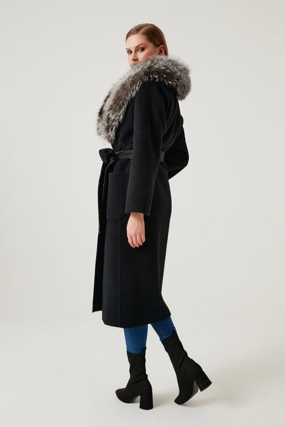 Woman wearing a black coat with a fur hood on a white background