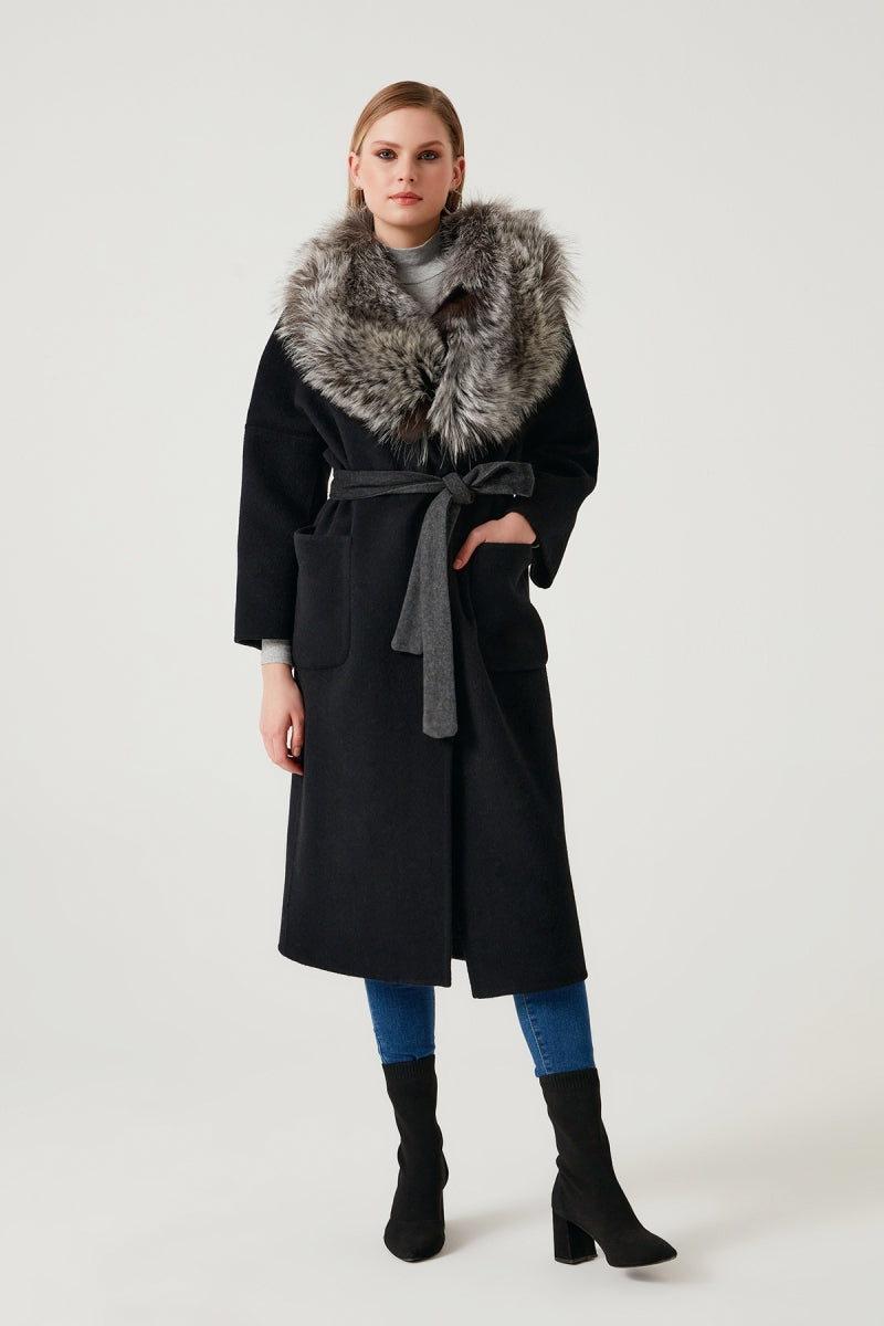 Woman wearing a black coat with a fur collar on a white background