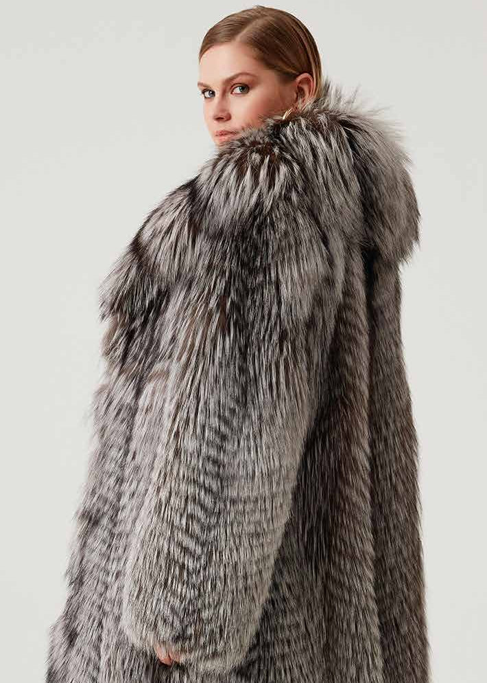 Woman wearing a long fur coat with a hood on a white background