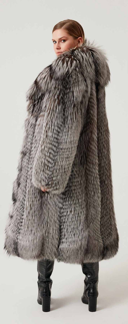 Woman wearing a long fur coat with a hood on a white background