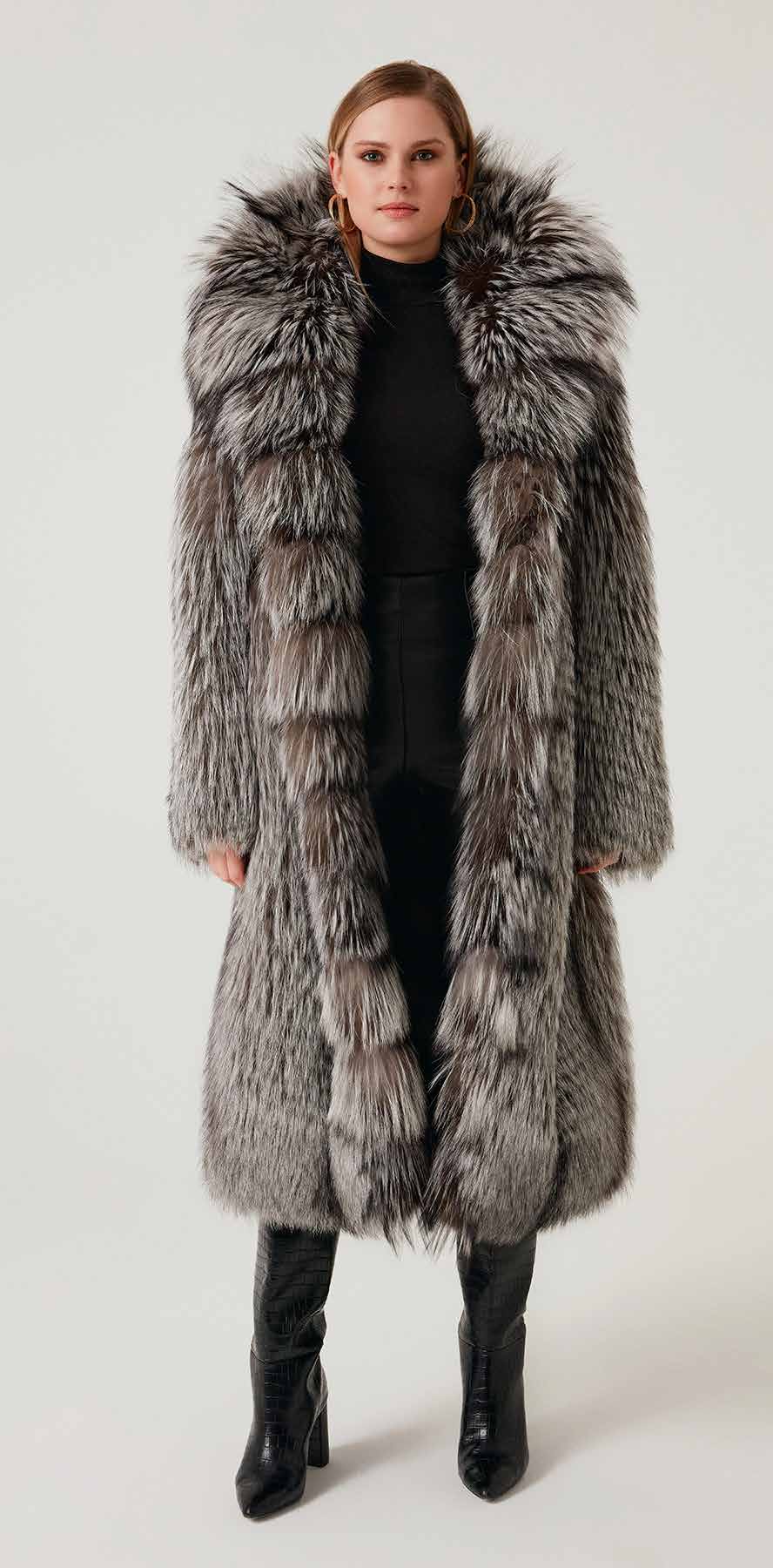 Woman wearing a long fur coat with a hood on a white background