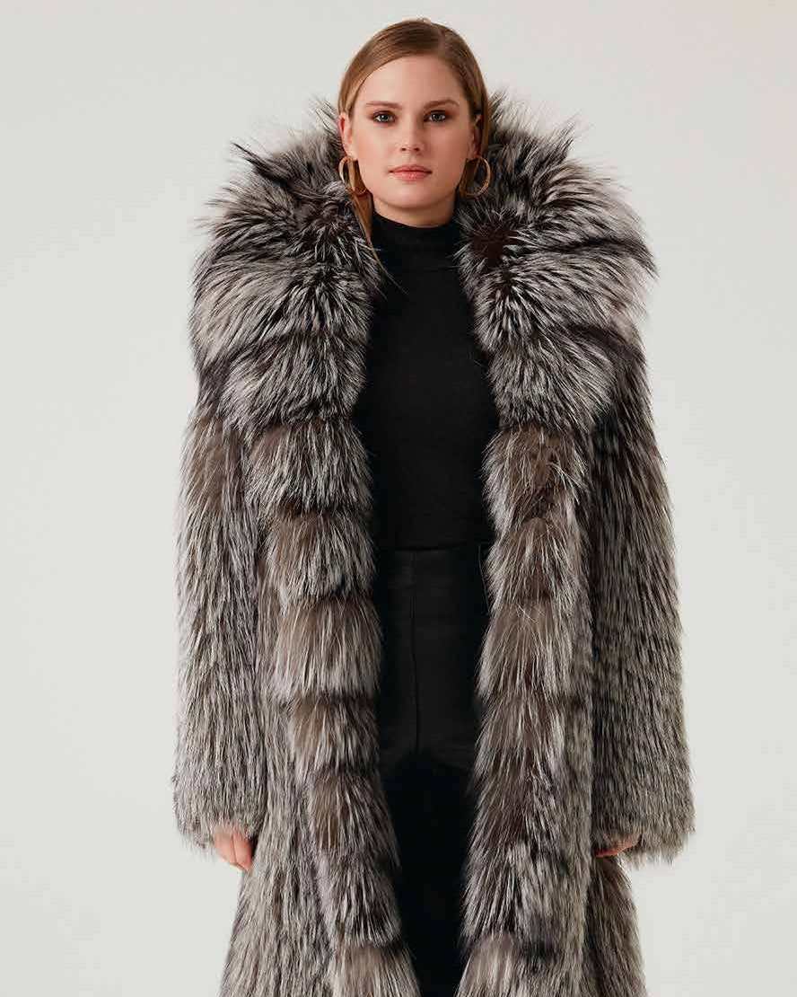 Woman wearing a long fur coat with a hood on a white background