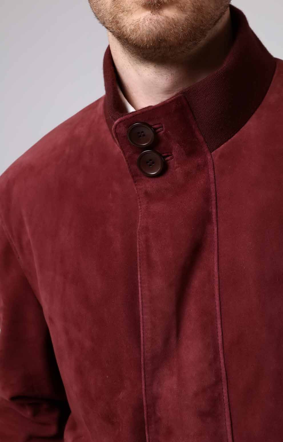 Close-up of a red suede jacket with two buttons on a plain background