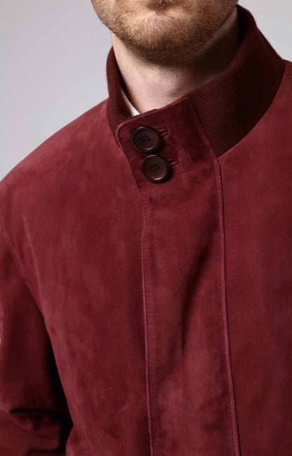 Close-up of a red suede jacket with two buttons on a plain background