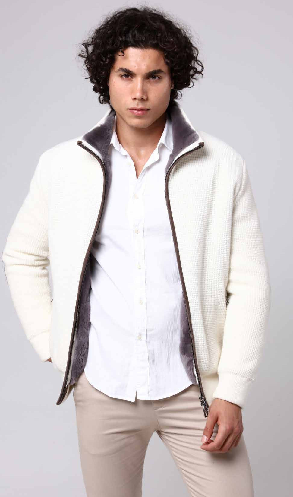 Man wearing a white shirt, cream jacket with gray lining, and beige pants on a light gray background