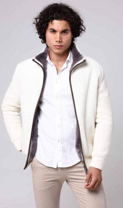 Man wearing a white shirt, cream jacket with gray lining, and beige pants on a light gray background